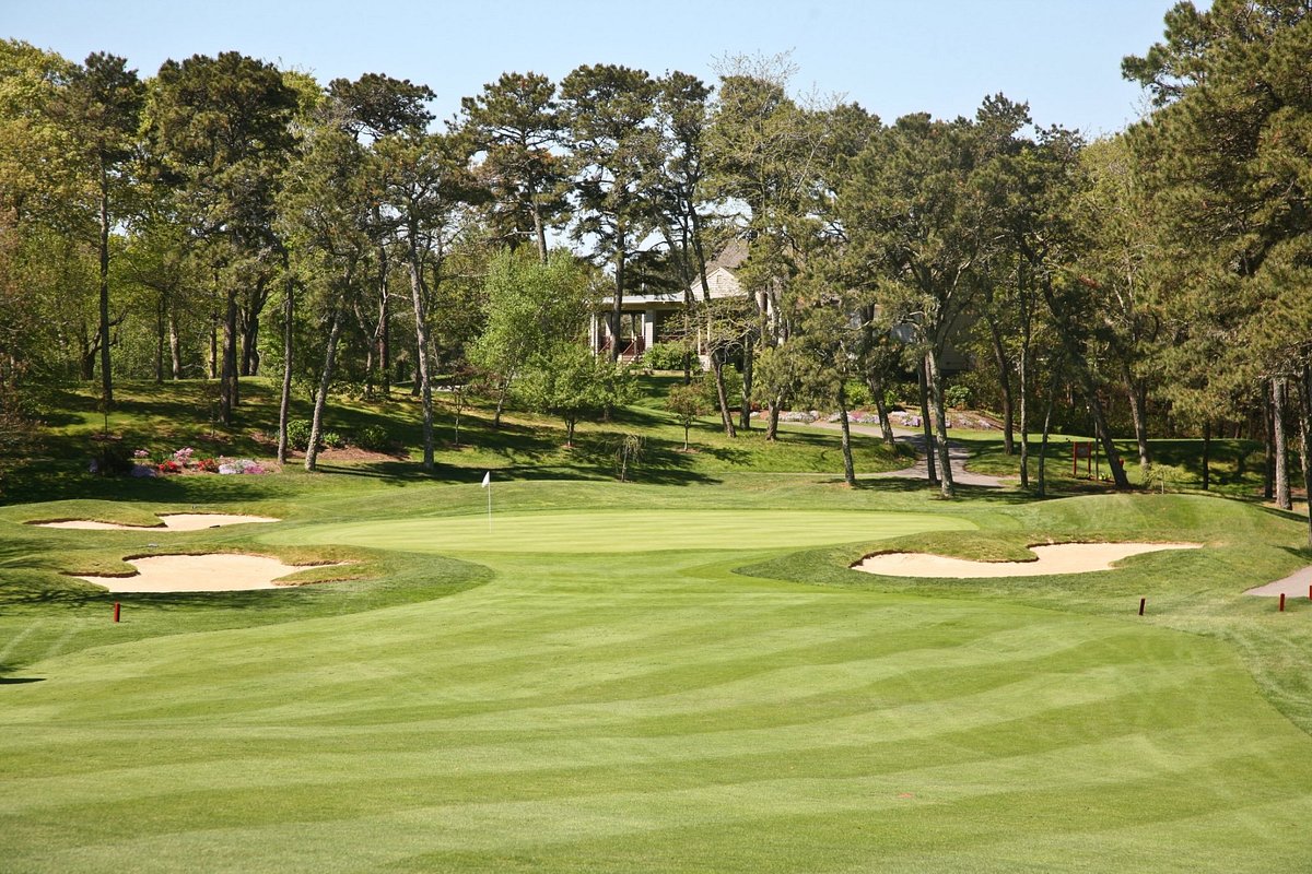 Lush fairway at Cranberry Valley Golf Course in Harwich, MA leading to a green surrounded by sand bunkers and tall trees
