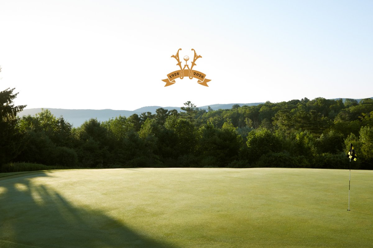 Early morning sunlight casts long shadows across a green at Wyndhurst Golf & Club in Lenox, MA, with forested hills in the background