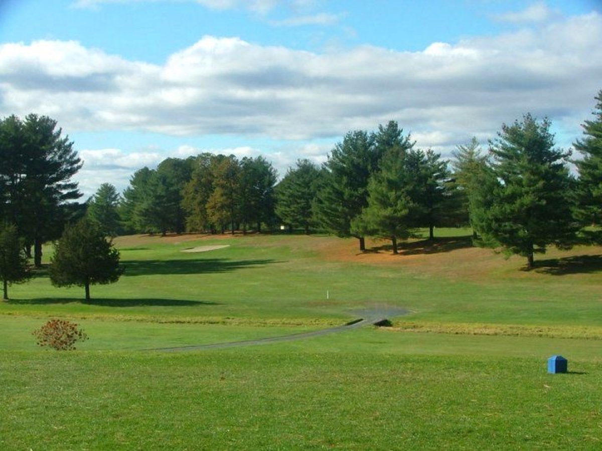 Wide fairway at East Mountain Country Club in Westfield, MA with scattered trees, sand bunker, and cloudy blue sky