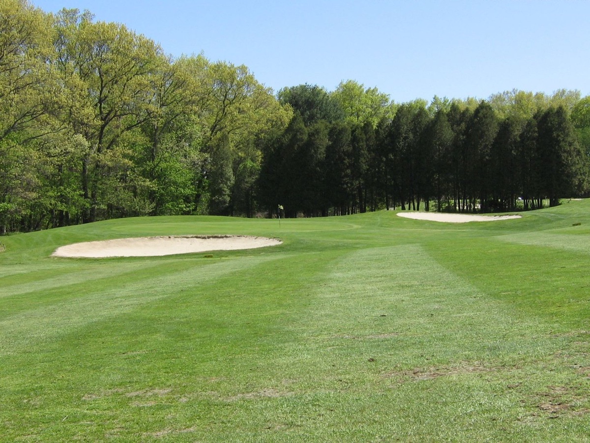 Wide fairway at Edgewood Golf Club in Southwick, MA with two sand bunkers, green grass, and trees bordering the hole under a clear sky