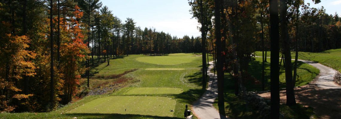 Tree-lined fairway at Bas Ridge Golf Course in Hinsdale, MA, with lush green tee boxes, winding cart path, and sunlight filtering through tall pines.