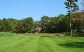 Wide fairway at Holly Ridge Golf Club in Sandwich, MA with green grass, trees lining the sides, and blue sky above