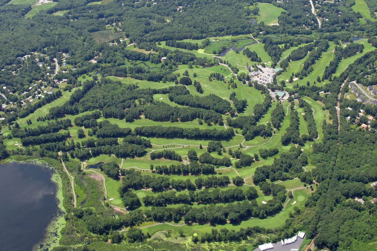 Aerial view of Juniper Hill GC Lakeside in Northborough, MA, featuring tree-lined fairways, greens, and a lake at the course edge.