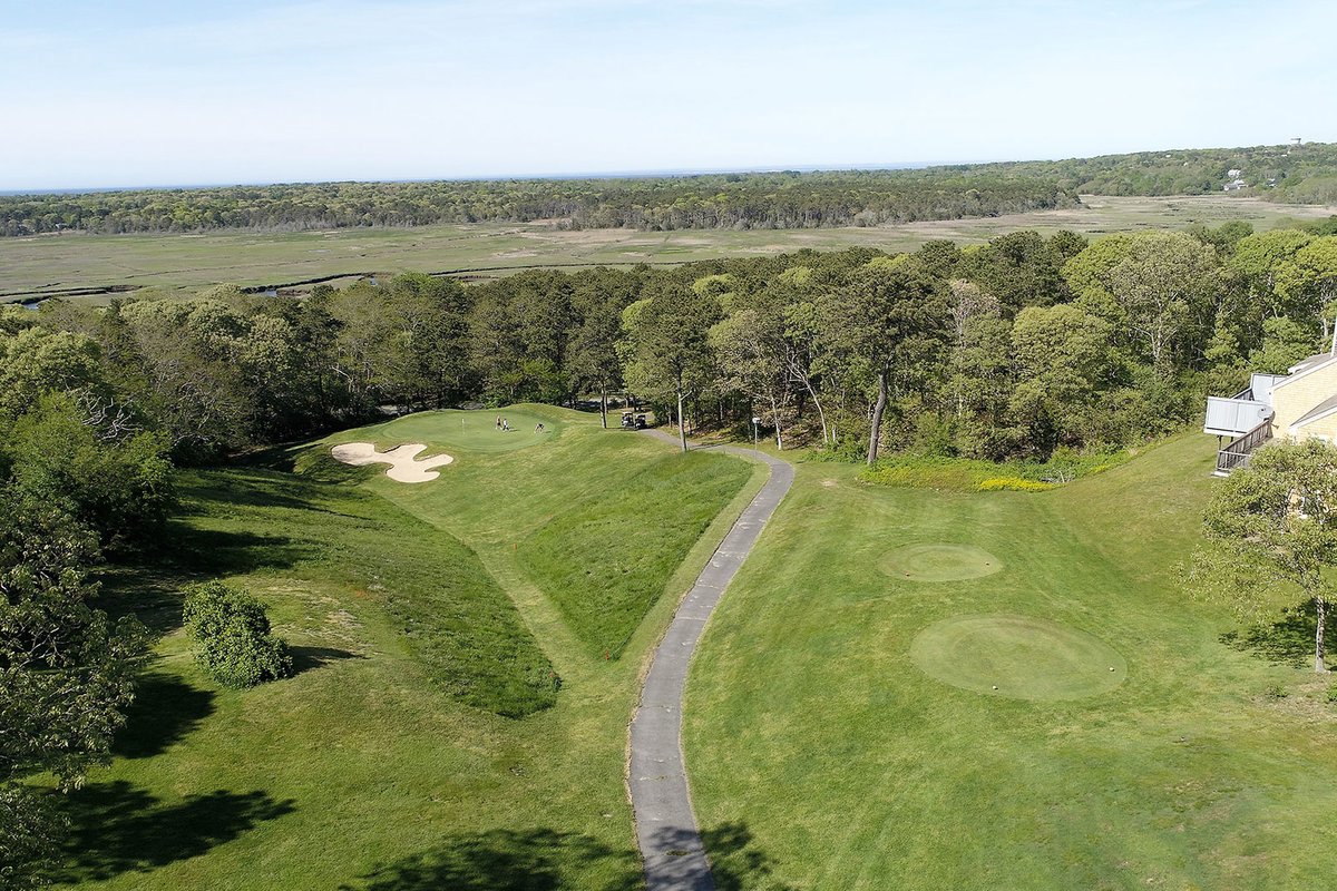 Aerial view of Kings Way Golf Course in Yarmouth, MA showing a fairway, sand bunkers, putting green, cart path, and surrounding trees.