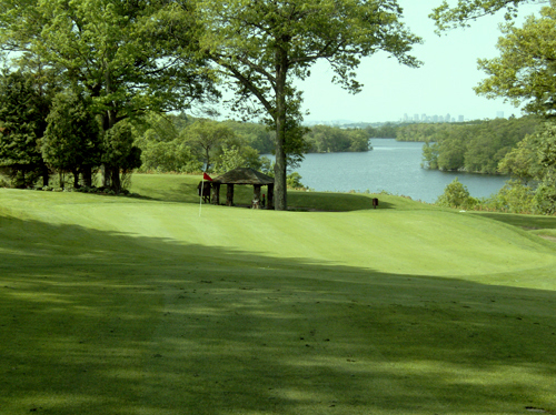 Lush fairway and green at Gannon Municipal GC in Lynn, MA with a flagstick, gazebo, trees, and large lake in the background