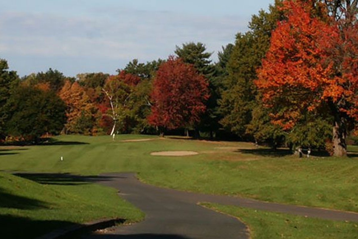 Tree-lined fairway at Oak Ridge Golf Club in Agawam, MA with vibrant autumn foliage and small sand bunker near green
