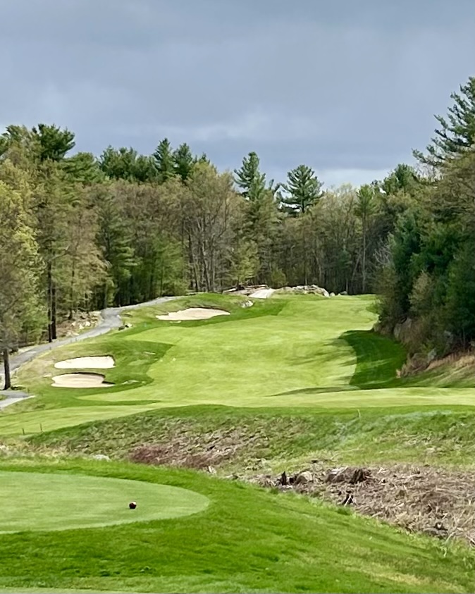 Shining Rock GC fairway with multiple bunkers, lush green grass, dense trees on both sides, and a cloudy sky above