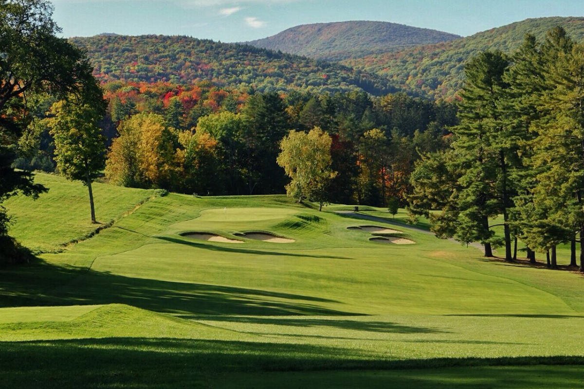 Expansive fairway and green at Taconic Golf Club with multiple bunkers, autumn trees, and rolling mountain backdrop