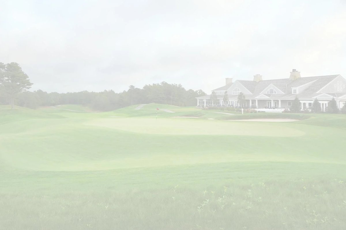 Expansive green fairway at Waverly Oaks Golf Club in Plymouth, MA with clubhouse and sand bunker under cloudy sky