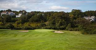 Rolling fairway at Chatham Seaside Links in Chatham, MA with two bunkers by the green, trees and houses in the background