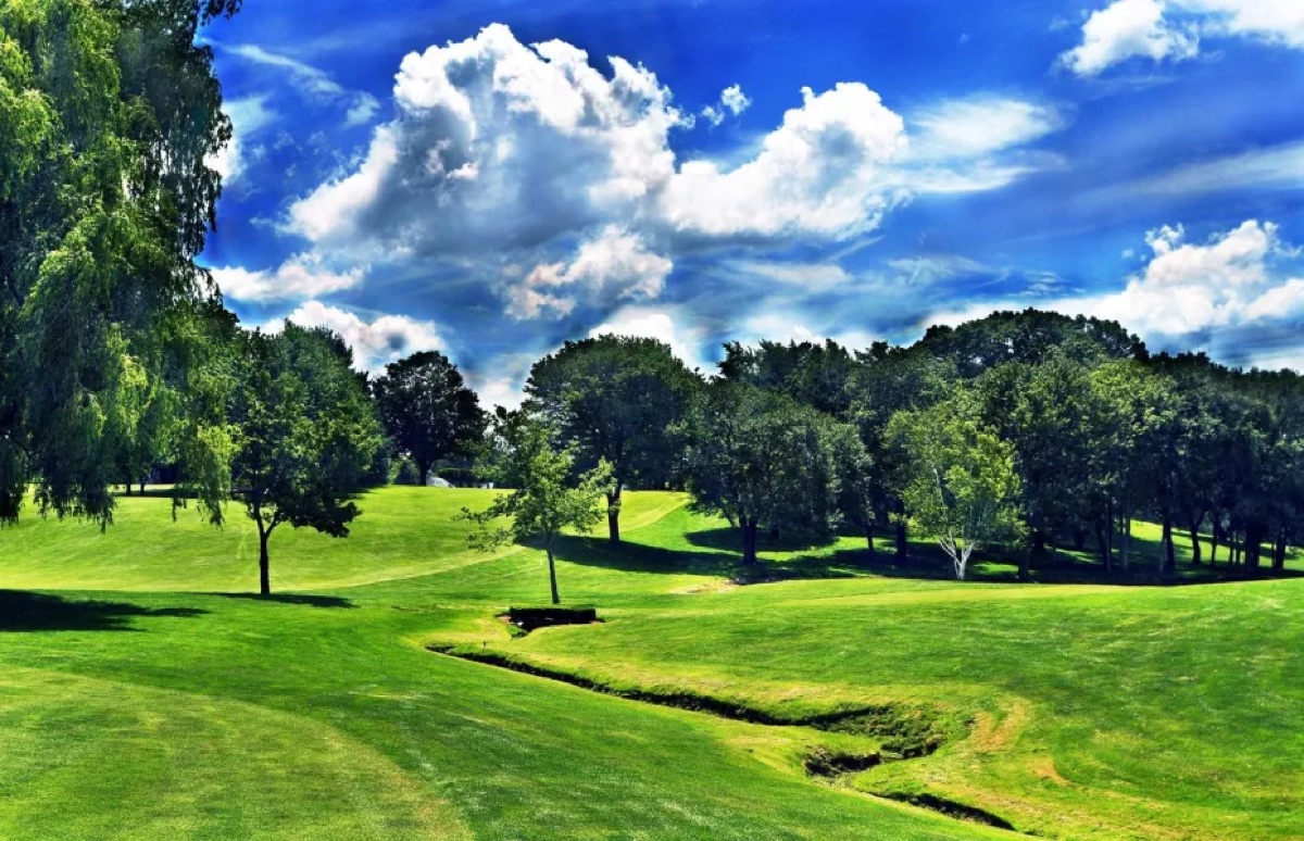 Lush fairways and greens at Chemawa Golf Course in North Attleborough, MA, bordered by trees under a partly cloudy blue sky