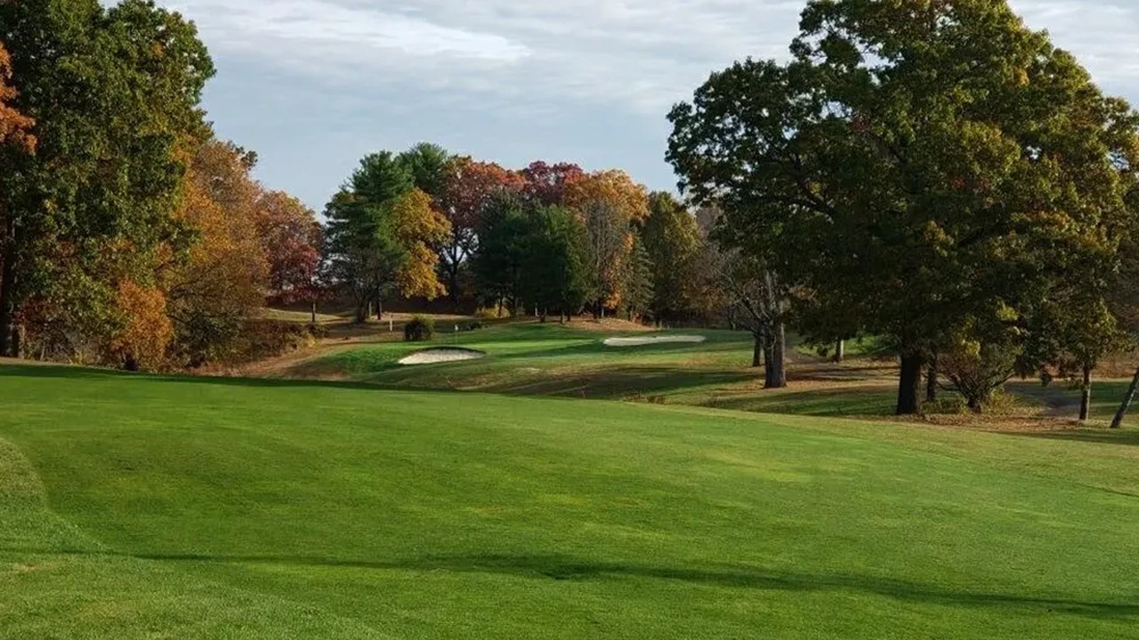 Rolling fairway at Wyckoff Country Club in Holyoke, MA with sand bunkers, mature trees, and fall foliage under a partly cloudy sky